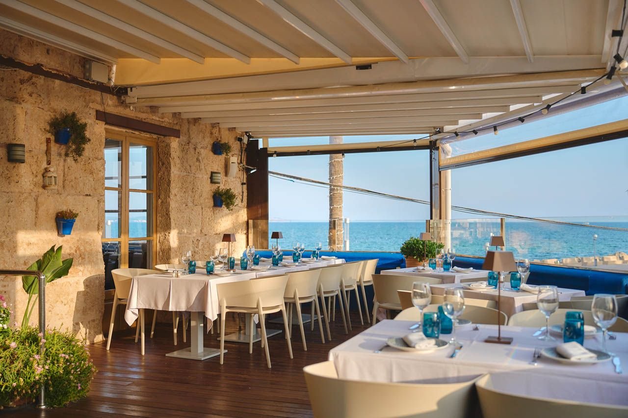 Terraza de Ola del Mar con mesas de mantel blanco y el mar detrás